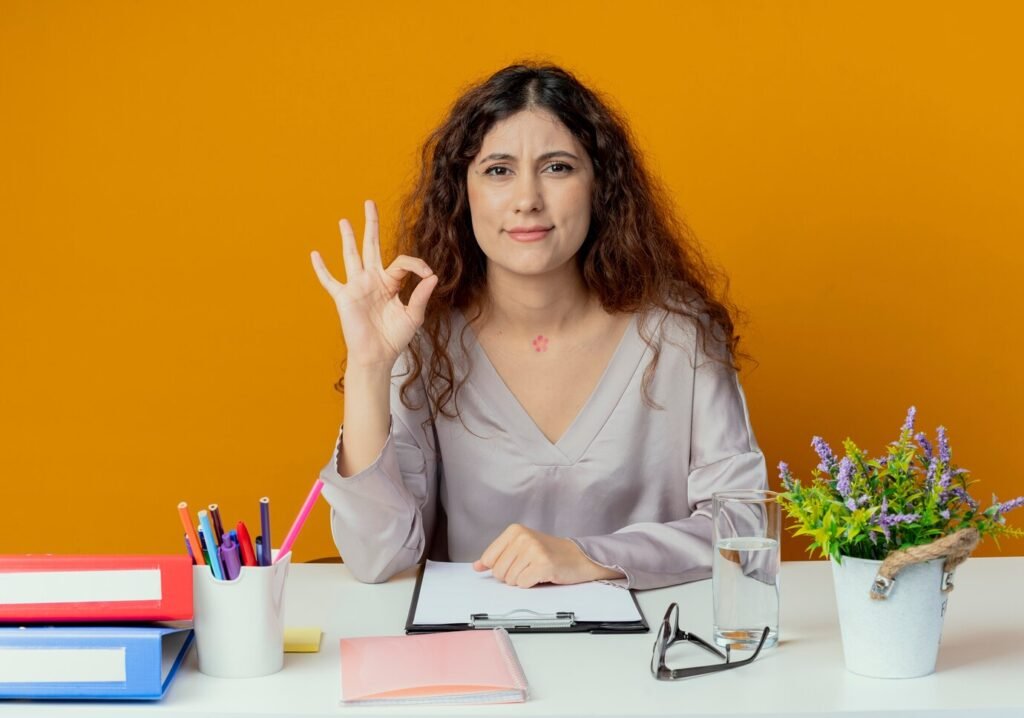 pleased-young-pretty-female-office-worker-sitting-desk-with-office-tools-showing-okey-gesture-isolated-orange_141793-73621-1024x718 The Comprehensive Why MBA Answer for Experienced Professionals-NotesMama 1