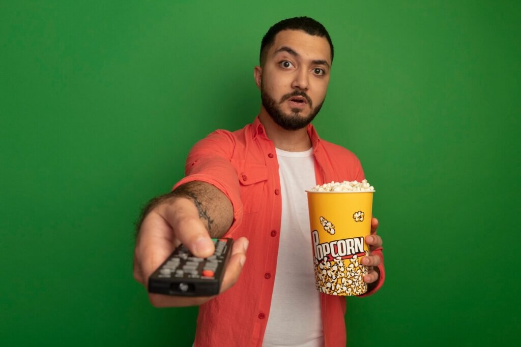 young-bearded-man-orange-shirt-holding-bucket-with-popcorn-using-tv-remote-looking-surprised-standing-green-wall_141793-61129-1024x683 Exploring the Fascinating World of Awafim Movies: A Comprehensive Guide to Must-Watch Films 2024